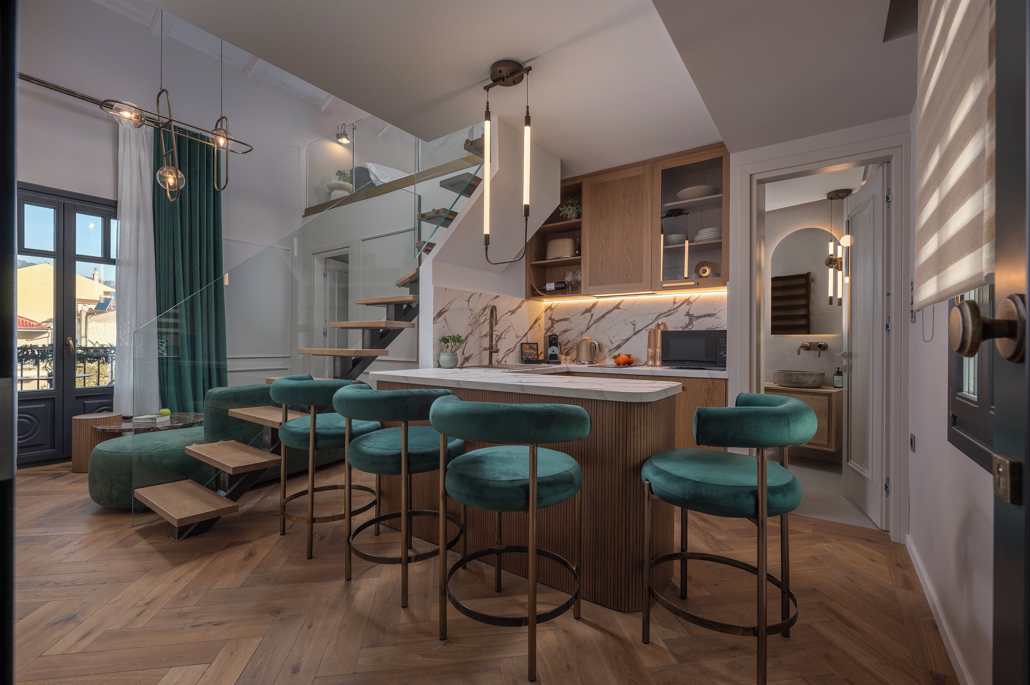 A modern kitchen with a bar area, wooden flooring, and a staircase.