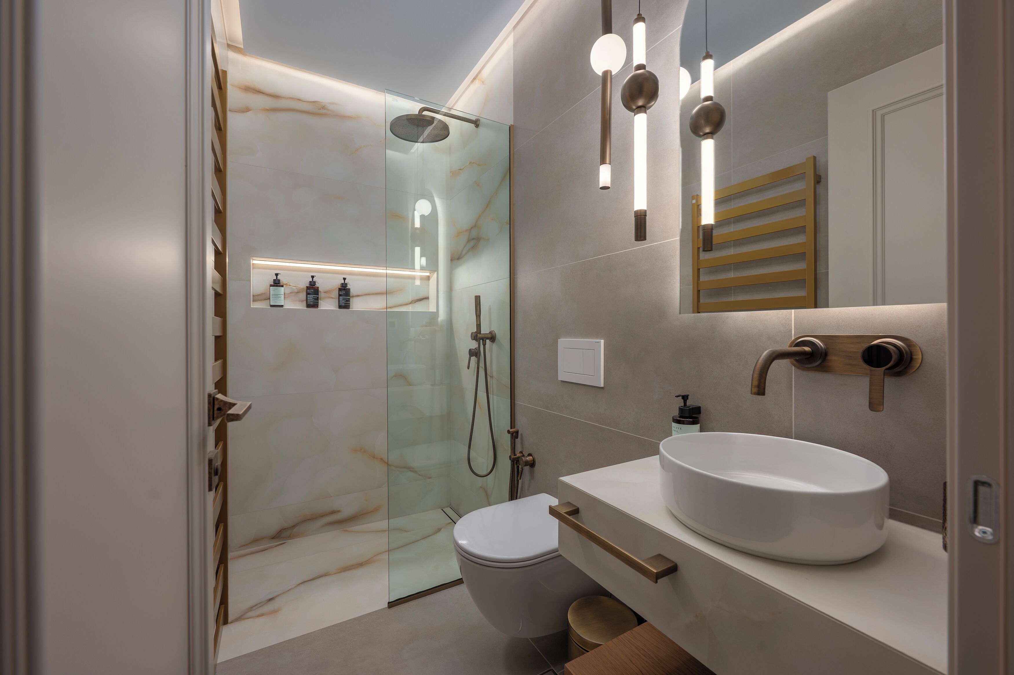 A modern bathroom with a glass-enclosed shower, a white sink, and a wooden towel rack.