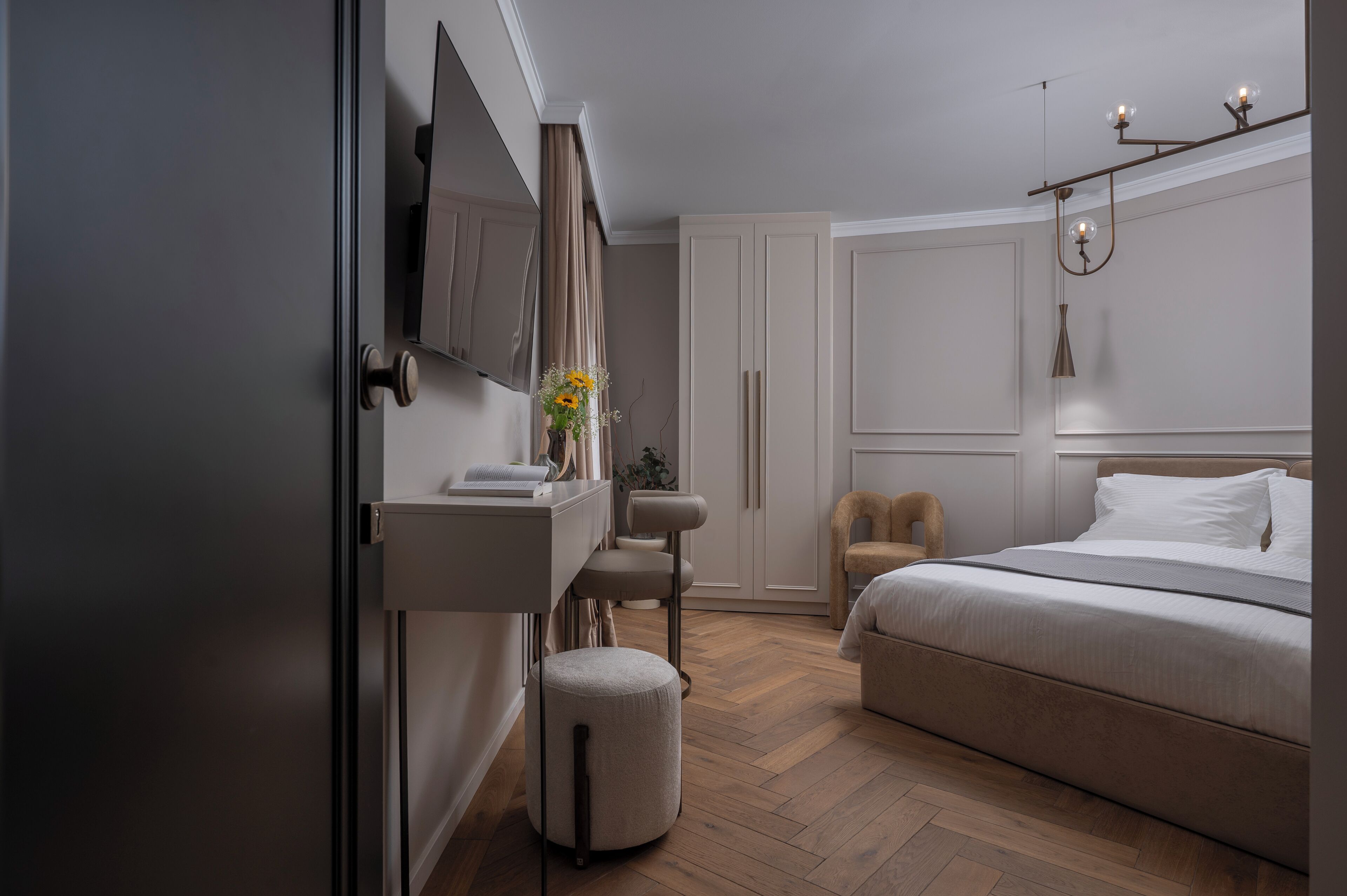 Une chambre à coucher moderne avec un lit, une coiffeuse, un miroir et un luminaire suspendu.