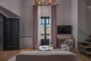 Un dormitorio moderno con cama, escritorio, silla, televisor y ventana con cortinas.