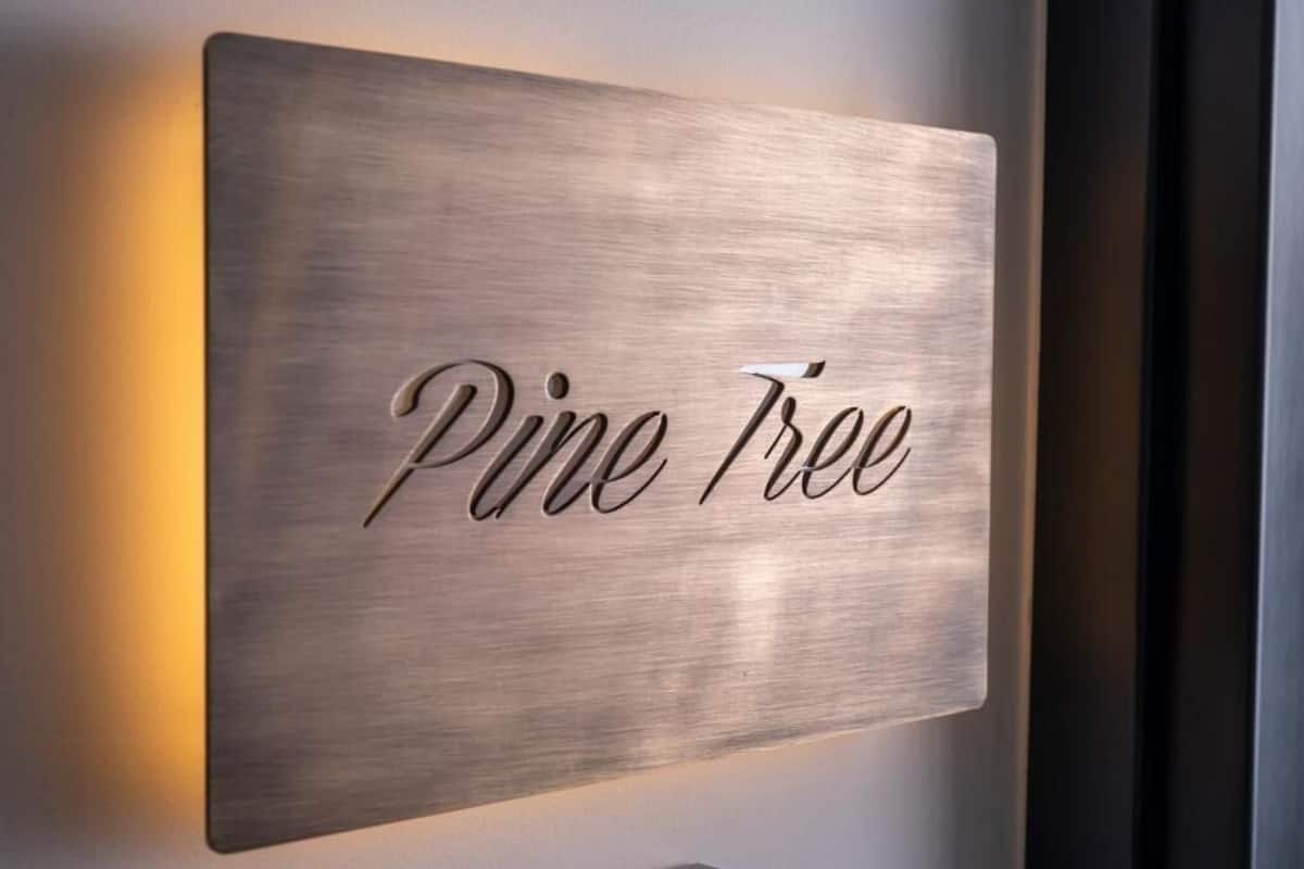 Un letrero en la pared con el texto 'Pine Tree' en una fuente cursiva.