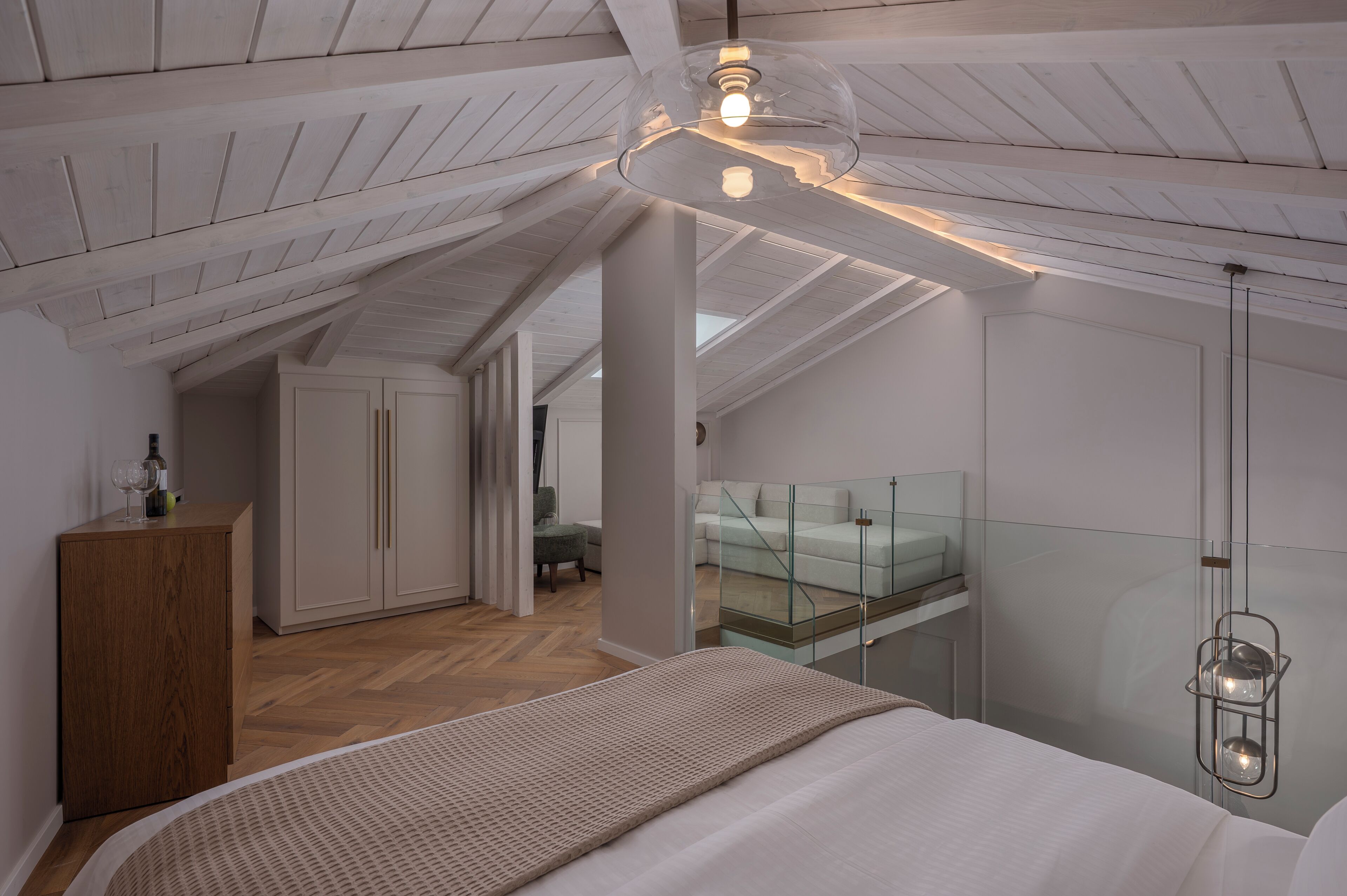 A bedroom with a bed, a wooden cabinet, a glass partition, and a hanging light fixture.