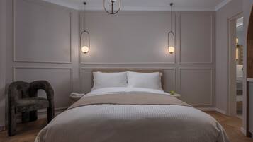 A bedroom with a large bed, two bedside tables, a chair, and pendant lighting.
