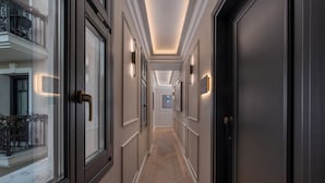Un pasillo con piso de espiga, puertas de madera oscura y apliques de pared.