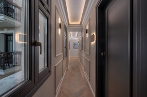 Un pasillo con piso de espiga, puertas de madera oscura y apliques de pared.