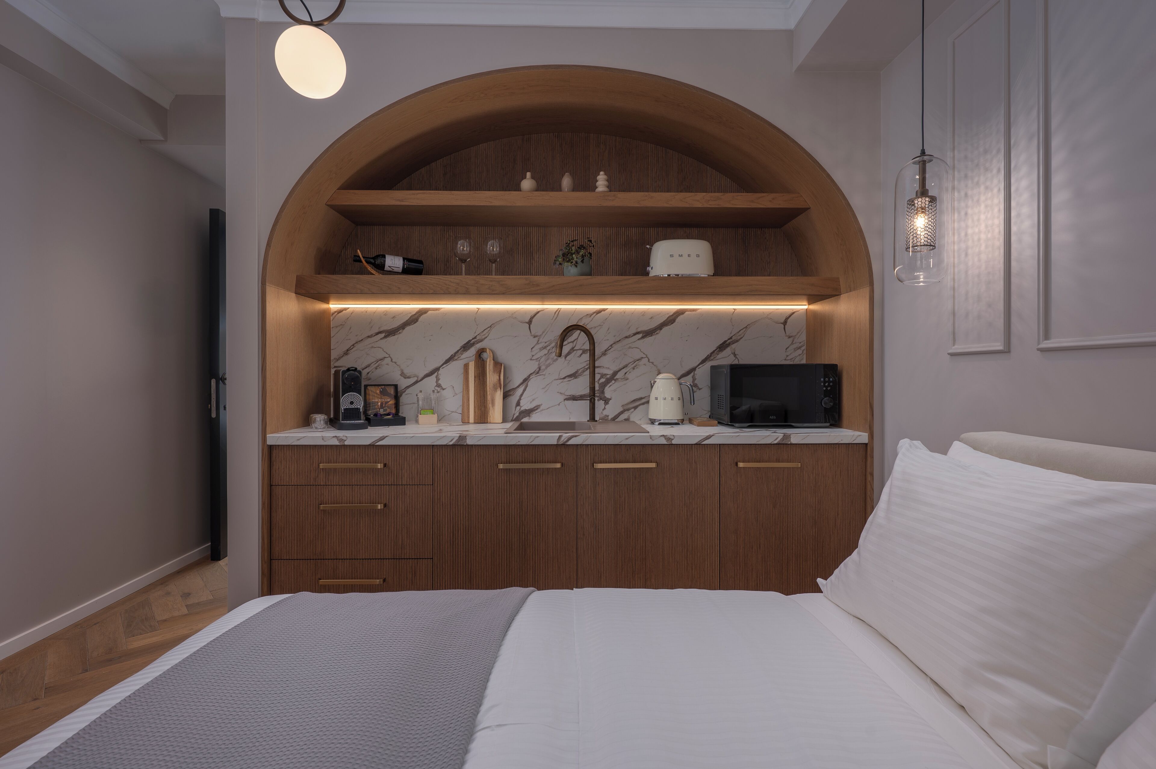 Ein Schlafzimmer mit einem Bett, einem gewölbten Holzboden über einer Marmorplatte und einem Fernseher links.