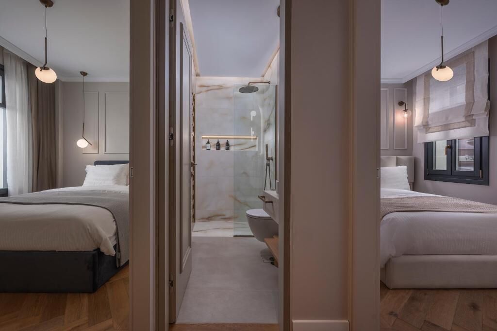 A modern hotel room with two beds, a shower, and a small bathroom.