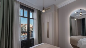 Una habitación de hotel con cama, un ventanal con cortinas, un armario y un espejo.