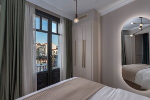 Una habitación de hotel con cama, un ventanal con cortinas, un armario y un espejo.