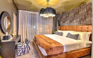 Ein Hotelzimmer mit einem großen Bett, einem Schreibtisch, einem Sessel und einer Wanddekoration.