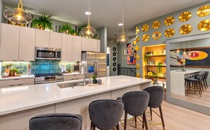 A modern kitchen with a central island, stainless steel appliances, and a dining area with bar stools. - Stylish 4BR/4BA, Pool | Hot Tub & Views. 11 Beds! (Nashville)