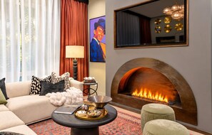 A living room with a sofa, a coffee table with decorative items, a fireplace, and a painting on the wall. - Stylish 4BR/4BA, Pool | Hot Tub & Views. 11 Beds! (Nashville)