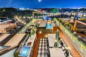 Eine Dachterrasse mit Sitzgelegenheiten im Freien, einem Pool und Lichterketten.