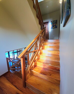 A wooden staircase with a railing, leading to a room with a view. - Placencia Villa for 8 guests, Beach, Luxury, Pool (Placencia)