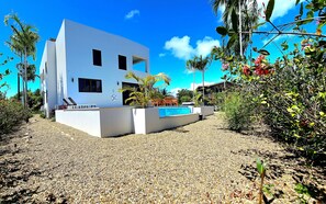 A modern two-story building with a swimming pool, surrounded by pebbles and tropical vegetation. - Placencia Villa for 8 guests, Beach, Luxury, Pool (Placencia)