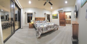 A bedroom with a bed, a desk, a chair, a ceiling fan, and a sliding door leading to a balcony. - Placencia Villa for 8 guests, Beach, Luxury, Pool (Placencia)
