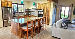 Una cocina con una isla central, armarios de madera y electrodomésticos de acero inoxidable, además de un comedor con sillas.