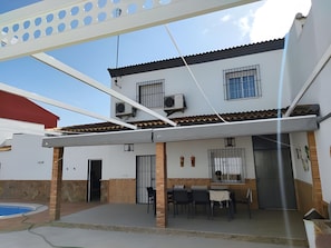 A two-story house with a covered patio, outdoor seating, and a swimming pool.
