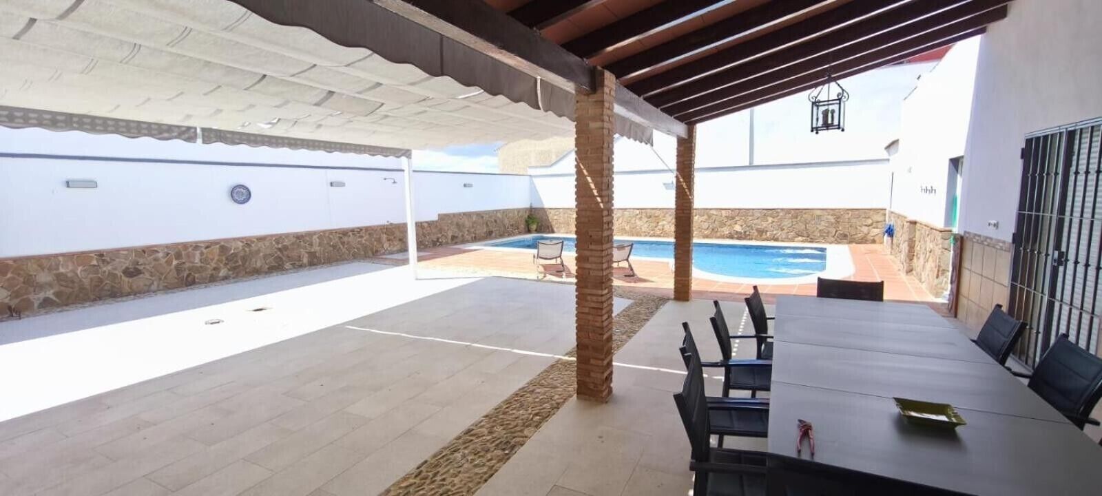 An outdoor patio with a pool, covered seating, and a stone wall.. Casa Jade – Spacious House with Pool and Barbecue in Fuente de Piedra