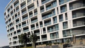 A modern building with a swimming pool, surrounded by greenery and a clear sky. - Elite Skyline Suite, Ellipse, Waterfall City (Midrand)