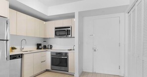 Eine kompakte Küche mit integriertem Mikrowellenherd, Kaffeeautomat und Backofen.