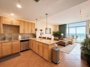 A modern kitchen with granite countertops, wooden cabinets, and a stainless steel dishwasher. - Sapphire 1605 - By GISO Vacation Rentals (South Padre Island)