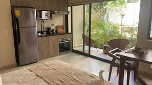 Eine moderne Küche mit Kühlschrank, Backofen und Mikrowelle. Ein Essbereich mit Tisch und Stühlen ist ebenfalls vorhanden.