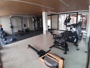 Ein Fitnessstudio mit Trainingsgeräten, einem Rudergerät und einem stationären Fahrrad.