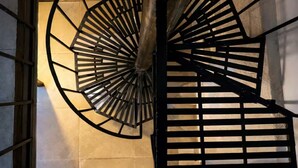 A spiral staircase with a wooden handrail and black metal railings. - Bowra Orquideas (Zapopan)