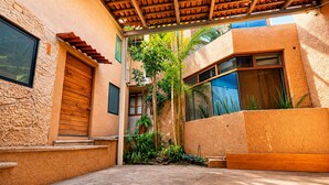 A courtyard with a wooden pergola, a concrete floor, and a small garden with plants. - Bowra Orquideas (Zapopan)