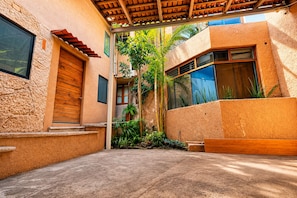 A courtyard with a wooden pergola, a concrete floor, and a small garden with plants.