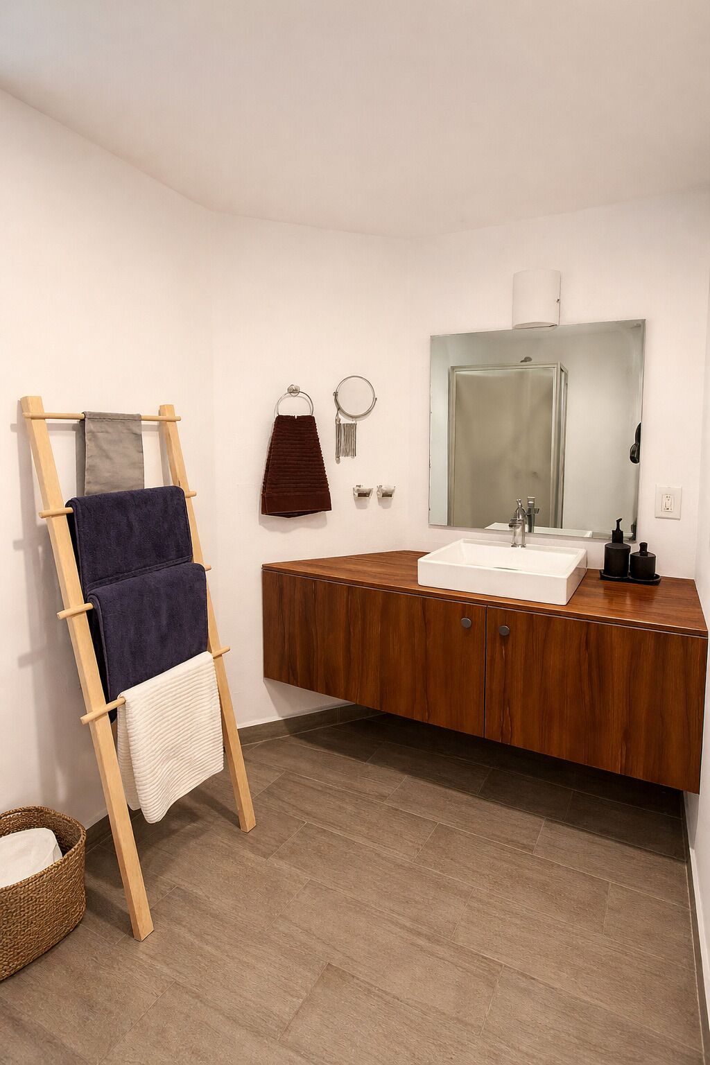 Un baño con tocador de madera, un espejo, un perchero y una escalera de madera.