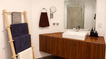 Un baño con tocador de madera, un espejo, un perchero y una escalera de madera.