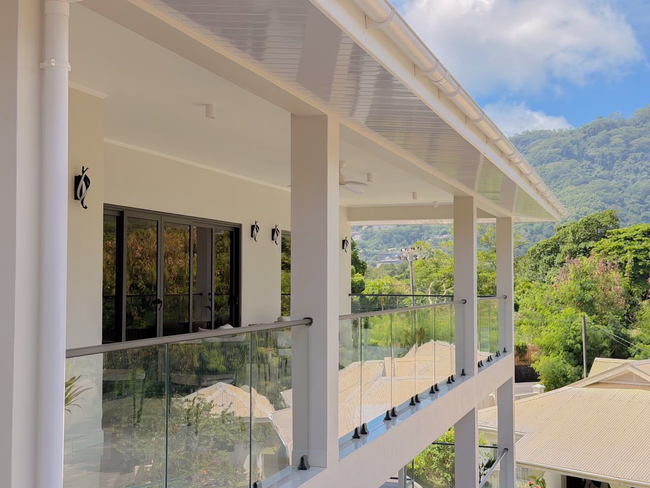 A modern building with a glass balcony overlooking a lush landscape.