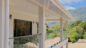 A modern building with a glass balcony overlooking a lush landscape.