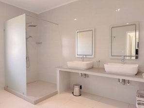 A modern bathroom with a glass-enclosed shower, two sinks, and mirrors above each sink. - Cove Holiday Apartments (Bel Ombre)