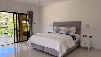A bedroom with a bed, a nightstand, a ceiling fan, and a view through a glass door.
