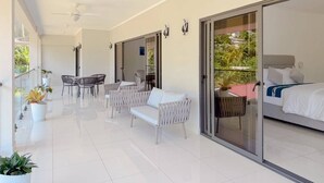 Een moderne hotelkamer met een balkon, witte meubels en een bed met een grijze hoofdbord.