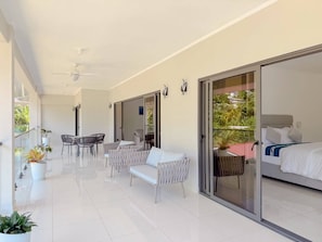 A modern hotel room with a balcony, white furniture, and a bed with a grey headboard. - Cove Holiday Apartments (Bel Ombre)