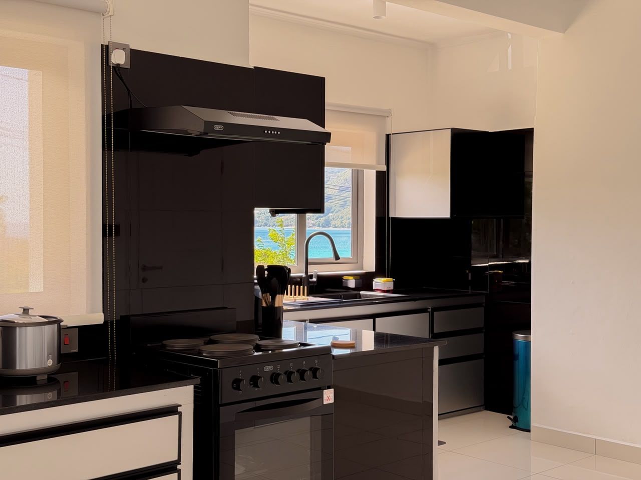 A modern kitchen with a stove, sink, and black cabinets.