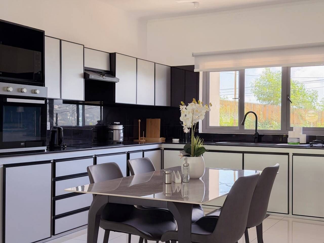 Una cucina moderna con zona pranzo, ampie finestre e vista sull'esterno.