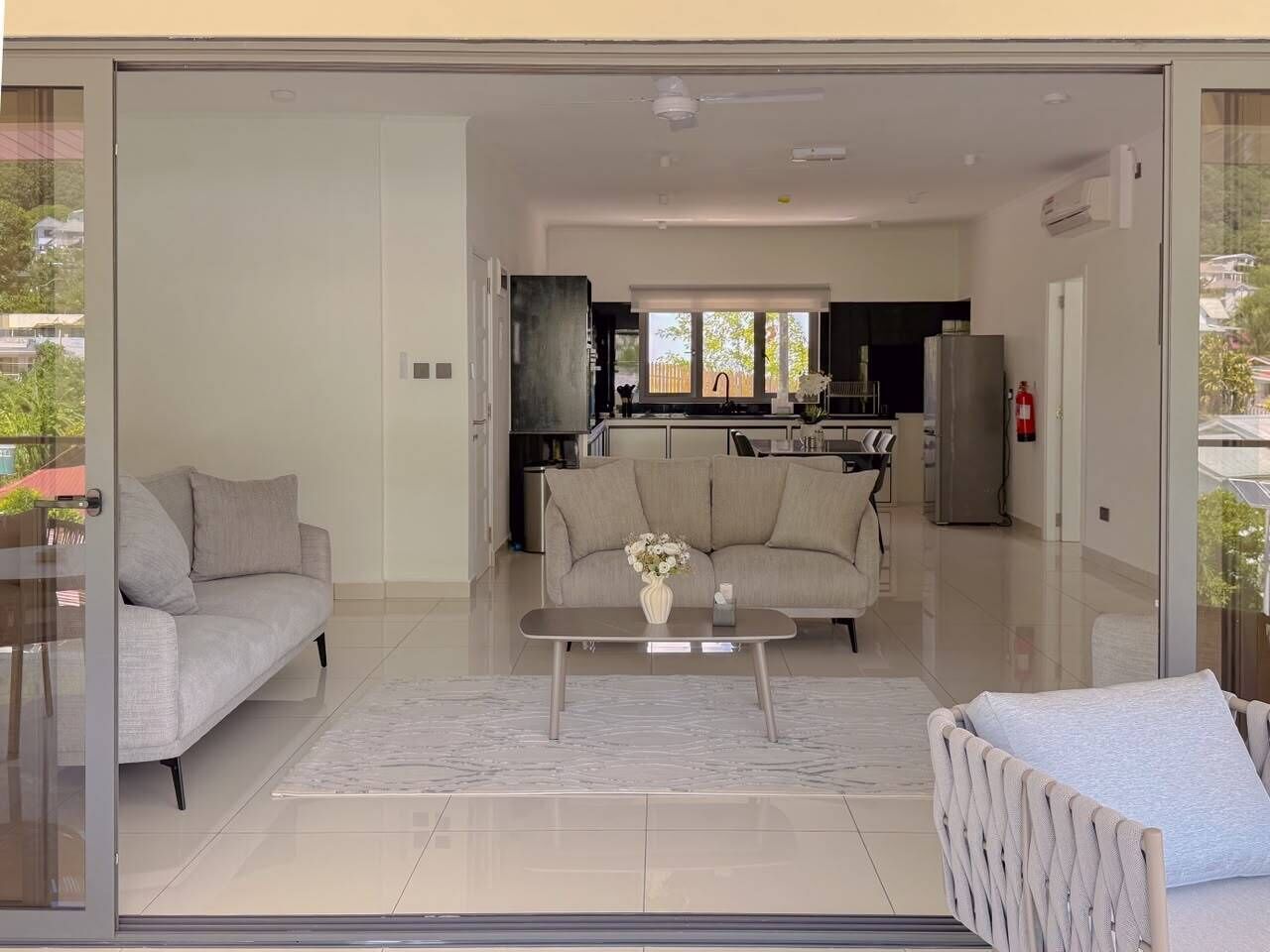 A modern living room with a sofa, a coffee table, and a view into the kitchen.