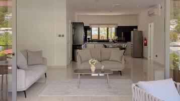A modern living room with a sofa, a coffee table, and a view into the kitchen.