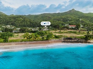 A coastal view with a beach, ocean, and a mountainous backdrop. - Cove Holiday Apartments (Mahe Island)
