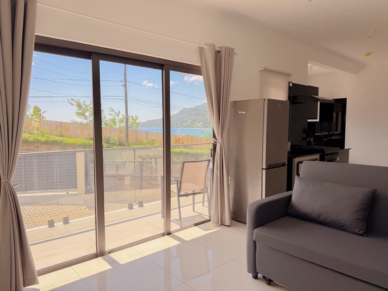 Ein modernes Wohnzimmer mit einer Couch, einem Flachbildfernseher und einer Schiebetür zu einem Balkon.