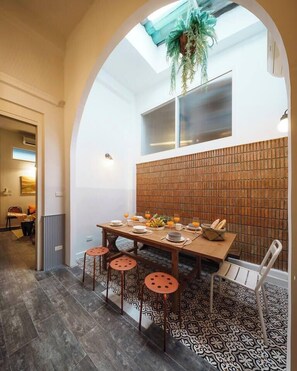 A dining area with a high table, stools, and a brick wall backdrop. - The Whole Shophouse · Book the Entire Building (Bang Rak)