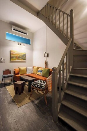 Una sala moderna con sofá, mesa de centro y escalera.