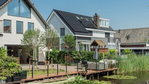 Ett modernt hus med ett stort glasfönster, en träveranda och en damm med näckrosor.