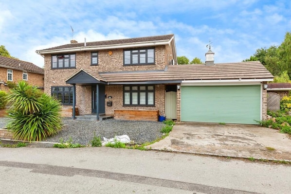 A two-story house with a garage, a front porch, and a small garden.