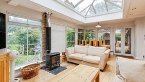 Una habitación amplia con un tragaluz grande, un sofá, una chimenea y un televisor.